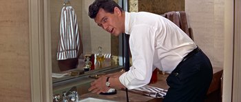 Movie still from “Pillow Talk” (1959), directed by Michael Gordon – A man in a white dress shirt and black tie looking in the mirror; Medium shot, Low angle