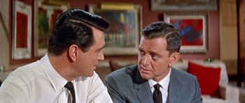 Movie still from “Pillow Talk” (1959), directed by Michael Gordon – Two men in suits talking to each other in front of a painting; Close Up shot, Over the shoulder angle