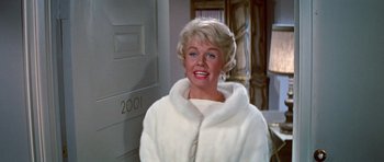 Movie still from “Pillow Talk” (1959), directed by Michael Gordon – A woman in a white coat standing in front of a door; Close Up shot, Low angle