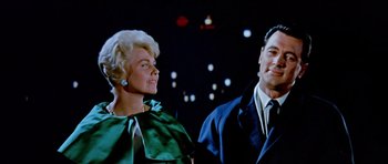 Movie still from “Pillow Talk” (1959), directed by Michael Gordon – A man and a woman standing next to each other in front of lights; Medium shot, Low angle