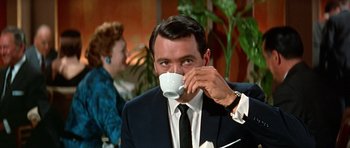 Movie still from “Pillow Talk” (1959), directed by Michael Gordon – A man in a suit and tie drinking from a white cup; Medium shot, Low angle