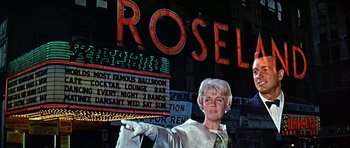 Movie still from “Pillow Talk” (1959), directed by Michael Gordon – A woman pointing at a sign in front of a building; Medium shot, Low angle