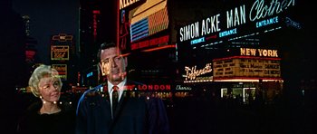 Movie still from “Pillow Talk” (1959), directed by Michael Gordon – A man standing in front of neon signs at night; Wide shot, Low angle