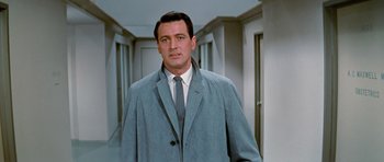 Movie still from “Pillow Talk” (1959), directed by Michael Gordon – A man in a suit and tie standing in a hallway; Medium shot, Low angle