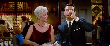 Movie still from “Pillow Talk” (1959), directed by Michael Gordon – An older woman and a younger man are sitting at a dinner table; Medium shot, Low angle