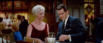 Movie still from “Pillow Talk” (1959), directed by Michael Gordon – An older woman sitting next to an older man at a table; Medium shot, Low angle