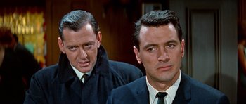 Movie still from “Pillow Talk” (1959), directed by Michael Gordon – Two men in suits and ties standing next to each other; Close Up shot, Over the shoulder angle