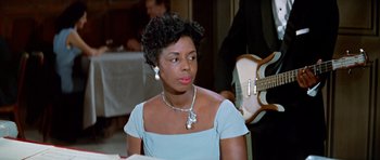 Movie still from “Pillow Talk” (1959), directed by Michael Gordon – A woman in a blue dress sitting in front of a guitar; Close Up shot, Over the shoulder angle