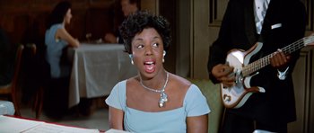 Movie still from “Pillow Talk” (1959), directed by Michael Gordon – A woman in a blue dress is sitting at a table; Close Up shot, Low angle