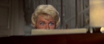 Movie still from “Pillow Talk” (1959), directed by Michael Gordon – A blonde woman with blue eyes looking over a table; Close Up shot, Low angle