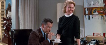 Movie still from “Pillow Talk” (1959), directed by Michael Gordon – A man and a woman sitting at a dining table; Medium shot, Low angle