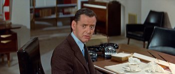 Movie still from “Pillow Talk” (1959), directed by Michael Gordon – An older man sitting at a desk in front of a phone; Close Up shot, High angle