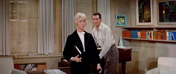 Movie still from “Pillow Talk” (1959), directed by Michael Gordon – A man and a woman standing next to each other in a room; Medium shot, Low angle