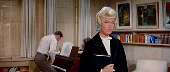 Movie still from “Pillow Talk” (1959), directed by Michael Gordon – A woman in a black jacket holding a book; Medium shot, Low angle