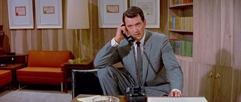 Movie still from “Pillow Talk” (1959), directed by Michael Gordon – A man sitting at a table talking on a phone; Medium shot, Low angle