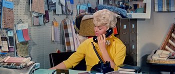 Movie still from “Pillow Talk” (1959), directed by Michael Gordon – A woman talking on a phone while sitting at a desk; Medium shot, High angle