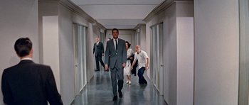 Movie still from “Pillow Talk” (1959), directed by Michael Gordon – A man in a suit walking down a hall way; Wide shot, Low angle