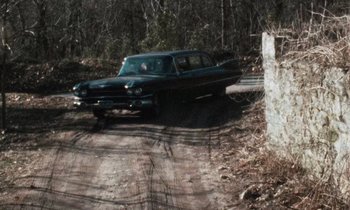 An old car is driving down a dirt road
