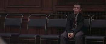 Movie still from “Pink Floyd: The Wall” (1982), directed by Alan Parker – A man sitting on a chair in a room; Medium shot, High angle