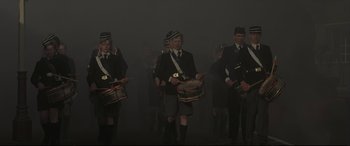 Movie still from “Pink Floyd: The Wall” (1982), directed by Alan Parker – A group of men in uniforms playing drums; Wide shot, High angle