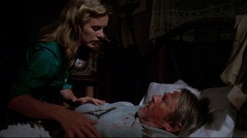Movie still from “Piranha” (1978), directed by Joe Dante – A woman standing next to a man laying in a bed; Medium shot, High angle