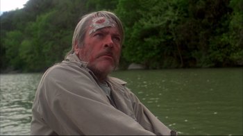 Movie still from “Piranha” (1978), directed by Joe Dante – A man sitting in a boat on a river; Close Up shot, Low angle