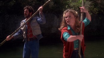 Movie still from “Piranha” (1978), directed by Joe Dante – A woman holding a stick in front of a man holding a pole; Medium shot, Low angle