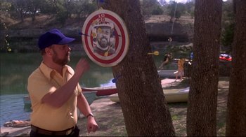 Movie still from “Piranha” (1978), directed by Joe Dante – A man holding an arrow in front of a tree; Medium shot, Over the shoulder angle