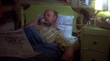Movie still from “Piranha” (1978), directed by Joe Dante – A man laying in a bed talking on a phone; Medium shot, High angle