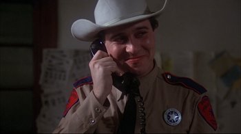 Movie still from “Piranha” (1978), directed by Joe Dante – A police officer talking on a phone wearing a cowboy hat; Close Up shot, Low angle