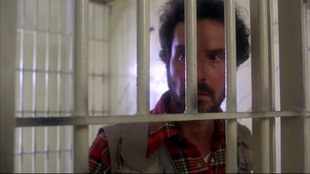 Movie still from “Piranha” (1978), directed by Joe Dante – A man behind bars looking through bars of a jail cell; Close Up shot, Low angle