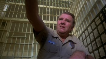 Movie still from “Piranha” (1978), directed by Joe Dante – A man in a jail cell raising his hand; Close Up shot, Low angle