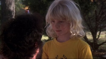 Movie still from “Piranha” (1978), directed by Joe Dante – A little girl with blonde curly hair wearing a yellow t - shirt; Close Up shot, Over the shoulder angle