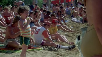Movie still from “Piranha” (1978), directed by Joe Dante – A group of people sitting on the beach watching a television; Wide shot, High angle