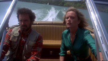 Movie still from “Piranha” (1978), directed by Joe Dante – A man and a woman sitting on a boat in front of a body of water; Medium shot, Low angle