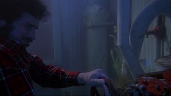 Movie still from “Piranha” (1978), directed by Joe Dante – A person holding a pair of scissors in a room; Medium shot, High angle