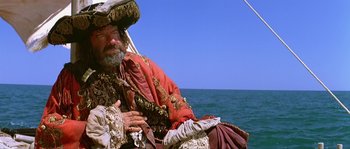 Movie still from “Pirates” (1986), directed by Roman Polanski – An old man sitting on a boat in the water; Medium shot, Low angle
