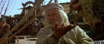 Movie still from “Pirates” (1986), directed by Roman Polanski – An old man smoking a pipe while sitting on a boat; Medium shot, Over the shoulder angle