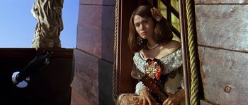 Movie still from “Pirates” (1986), directed by Roman Polanski – A young woman in a dress holding a guitar; Medium shot, Low angle