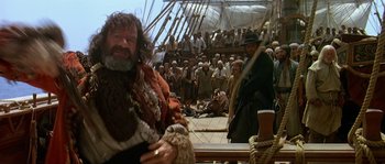 Movie still from “Pirates” (1986), directed by Roman Polanski – An old man with a long beard is standing in front of a group of people; Medium shot, Low angle