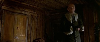 Movie still from “Pirates” (1986), directed by Roman Polanski – A man standing inside of a room with a wall; Medium shot, Low angle