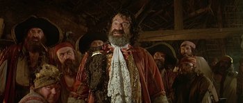 Movie still from “Pirates” (1986), directed by Roman Polanski – A man with a long beard wearing a red and white suit; Medium shot, Over the shoulder angle