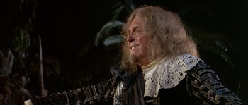 Movie still from “Pirates” (1986), directed by Roman Polanski – An old man with long white hair wearing a black and white dress; Close Up shot, Over the shoulder angle