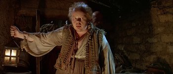 Movie still from “Pirates” (1986), directed by Roman Polanski – A man with a beard is standing in a cave; Medium shot, Low angle