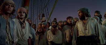 Movie still from “Pirates” (1986), directed by Roman Polanski – A large group of men standing next to each other on a boat; Medium shot, Low angle