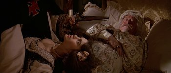 Movie still from “Pirates” (1986), directed by Roman Polanski – A woman laying on a bed holding a gun; Medium shot, Overhead angle
