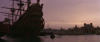 Movie still from “Pirates” (1986), directed by Roman Polanski – A boat in a body of water next to a large building; Extreme Wide shot, Low angle