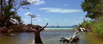 Movie still from “Pirates” (1986), directed by Roman Polanski – A man standing in the water with his arms raised; Extreme Wide shot, High angle