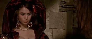 Movie still from “Pirates” (1986), directed by Roman Polanski – A beautiful young woman wearing a red dress and pearls; Close Up shot, Over the shoulder angle