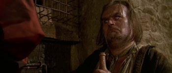 Movie still from “Pirates” (1986), directed by Roman Polanski – A man with a beard is holding a bottle; Close Up shot, Low angle